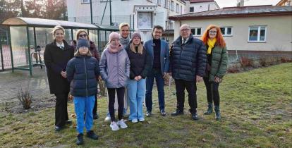 Grupa osób stoi przed stacją meterologiczną.