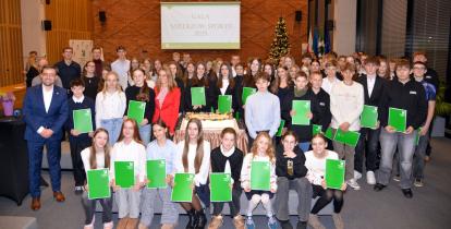 Uczestnicy gali sportowej wraz z burmistrzem Michałem Wiśniewskim pozują do wspólnego zdjęcia zbiorowego.