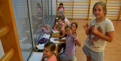 Zdjęcie grupy uśmiechniętych dzieci rysujących w sali gimnastycznej.