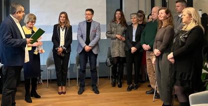 Grupa osób stoi w sali urzędu podczas świątecznego spotkania, w trakcie którego wręczane są podziękowania członkom Rady Seniorów.