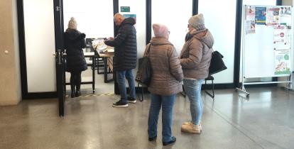 Grupa osób stoi przed wejściem do sali