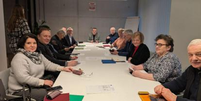 Zdjęcie grupy ludzi siedzącej przy stole w sali konferencyjnej.