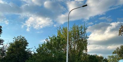 Na zdjęciu widać nowo zamontowaną latarnię uliczną przy ul. Literatów. Słup z oprawą LED stoi przy jezdni w pobliżu przystanku autobusowego, a w tle znajdują się drzewa i chodnik. Nowe oświetlenie poprawia bezpieczeństwo i widoczność po zmroku.