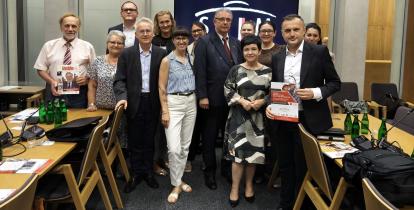 Grupa uczestników posiedzenia Parlamentarnego Zespołu ds. Seniorów pozuje do wspólnego zdjęcia w sali obrad.
