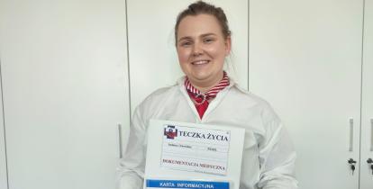 Kobieta trzyma w rękach teczkę życia, kopertę życia i kartę ICE