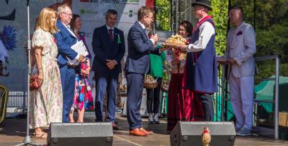 Na scenie przedstawiciele samorządu odbierają od starostów bochen chleba. 