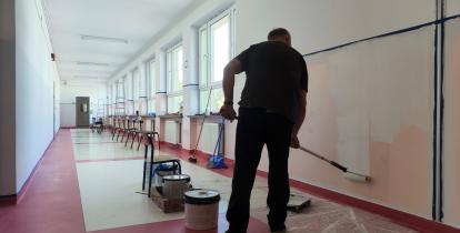 Mężczyzna maluje szkolny korytarz