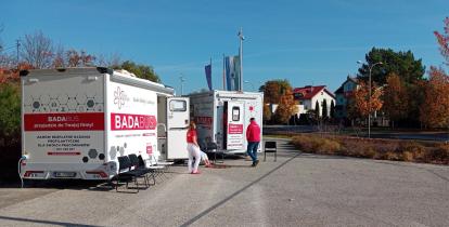 Przed urzędem stoją dwa mobilne gabinety medyczne oznaczone napisem „Badabus”, przy których znajdują się pracownicy oraz krzesła dla oczekujących pacjentów.