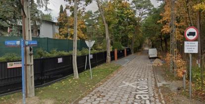 Ulica Łąkowa z nawierzchnią z betonowej trylinki, otoczona drzewami i ogrodzeniami, z widocznym oznakowaniem drogowym oraz zaparkowanym białym samochodem dostawczym.