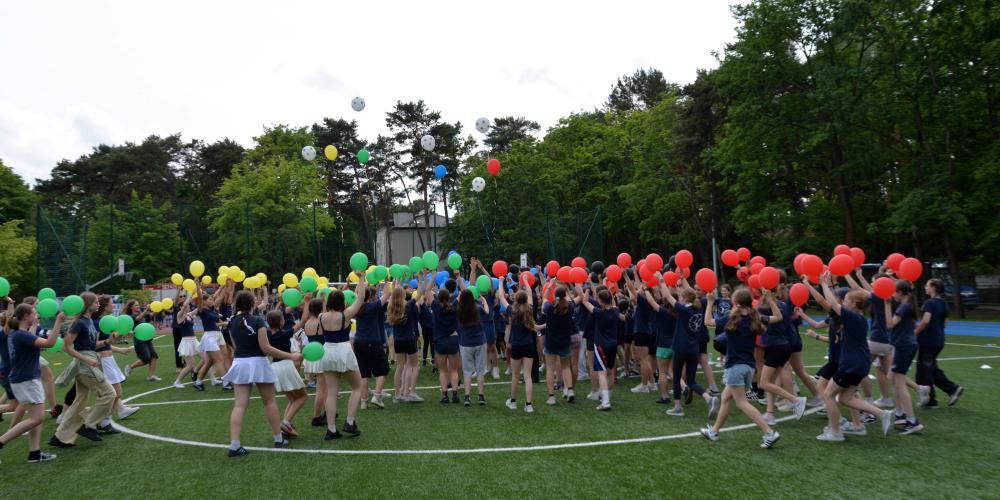 Dzieci na boisku z kolorowymi balonami
