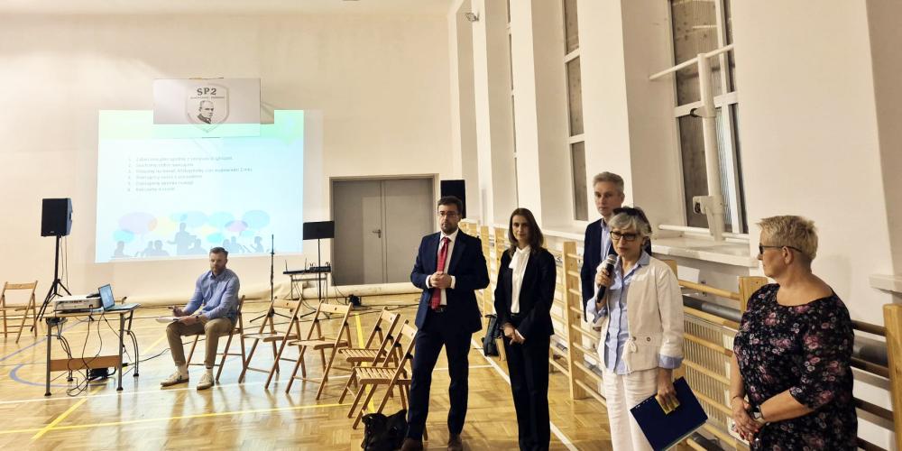 Grupa osób na sali gminastycznej.