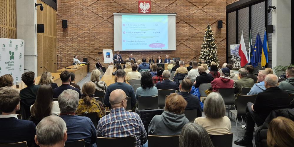 Grupa osób siedzi na sali posiedzeń.
