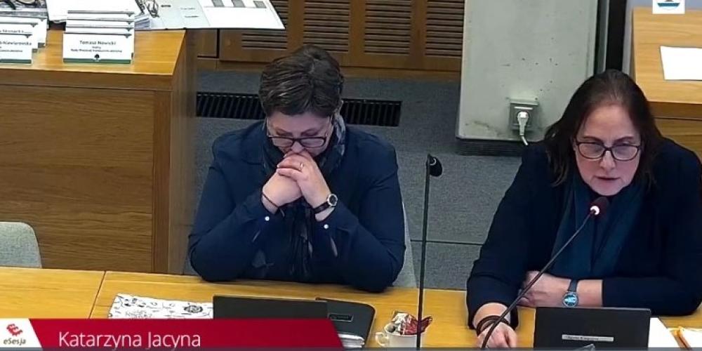 Dwie kobiety przy stole, jedna mówi do mikrofonu