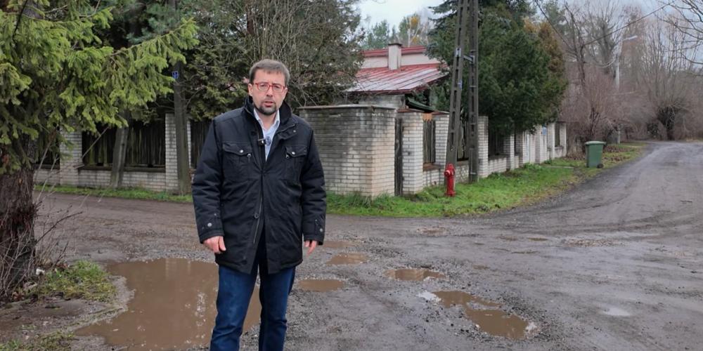 Meżczyzna stoi na nieutwardzonej drodze 