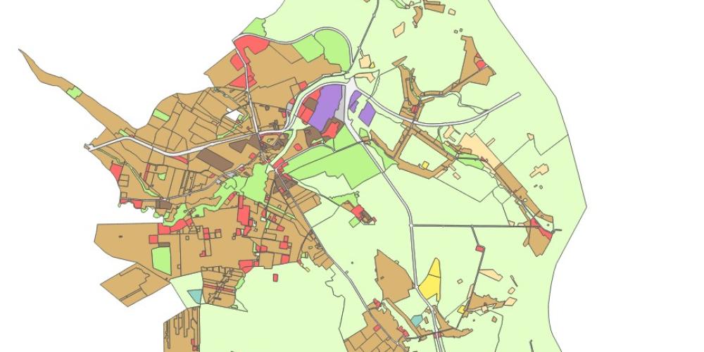 Mapa planistyczna gminy przedstawiająca zróżnicowane przeznaczenie terenów w formie kolorowych stref, z dominującą zabudową w części centralnej oraz rozległymi obszarami zielonymi na obrzeżach.