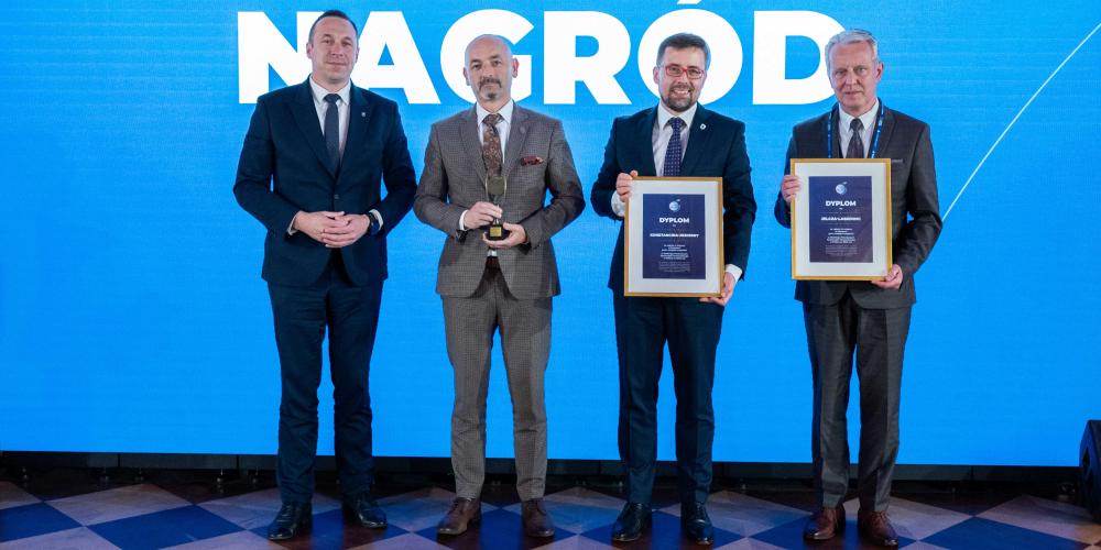 Na scenie gali wręczenia nagród przedstawiciele samorządów pozują z dyplomami i statuetką przy tle z napisem „Gala wręczenia nagród”.