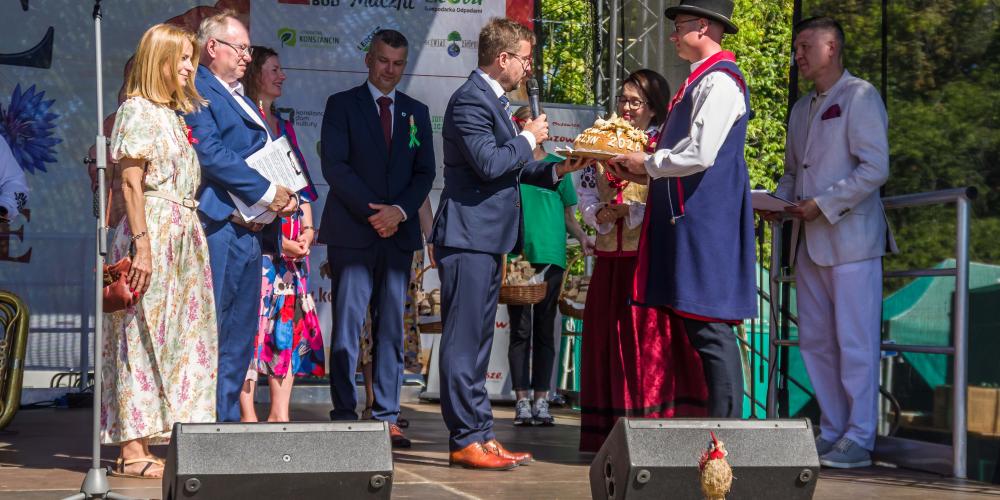 Na scenie przedstawiciele samorządu odbierają od starostów bochen chleba. 
