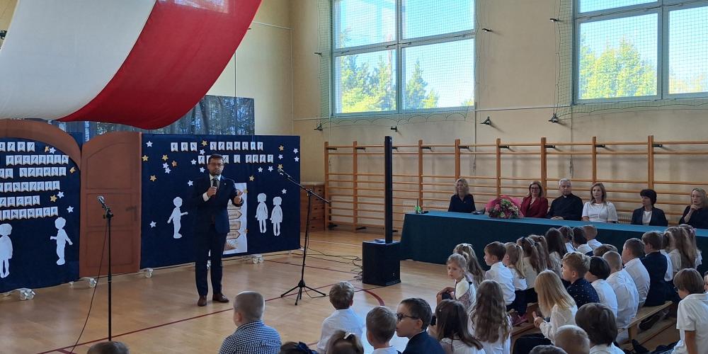 Uroczysty apel z okazji rozpoczęcia roku szkolnego w sali gimnastycznej, podczas którego burmistrz przemawia do zgromadzonych uczniów i nauczycieli.