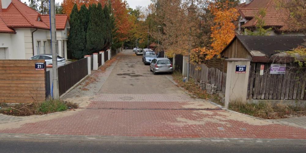 Widok wewnętrznego odcinka ul. Kazimierza Pułaskiego z kostką brukową, zaparkowanymi samochodami i jesiennymi drzewami wzdłuż posesji.