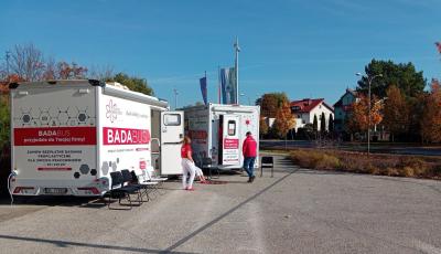 Przed urzędem stoją dwa mobilne gabinety medyczne oznaczone napisem „Badabus”, przy których znajdują się pracownicy oraz krzesła dla oczekujących pacjentów.