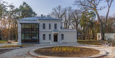 Widok na odrestaurowany budynek willi Kamilin od ulicy Piłsudskiego, z ozdobną drewnianą werandą. Przed budynkiem znajduje się ciąg komunikacyjny z dużym rondem przeznaczonym na nasadzenia ozdobne