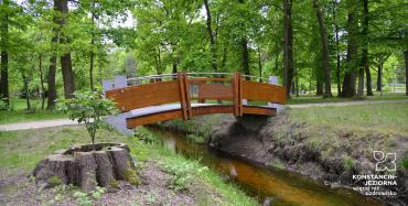 Drewniany mostek w parku, pod nim mała rzeka,  zdjęcie ilustrujące opisaną w artykule sytuację