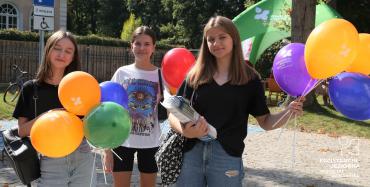 Park Zdrojowy. Trzy młode dziewczyny stoją obok siebie. Każda w rękach trzyma kolorowe balony z napisem Konstancin-Jeziorna więcej niż uzdrowisko. 