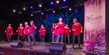 Na scenie występuje grupa dwunastu osób – dziesięć kobiet i dwóch mężczyzn. Każdy ubrany jest w czarne spodnie i czerwoną bluzkę. 