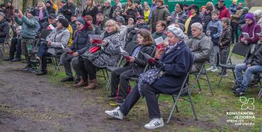 6.	Ludzie siedzą na krzesełkach i stoją na trawniku. Trzymają śpiewniki i śpiewają.