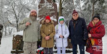 Dwie dziewczynki, dwóch starszych mężczyzn i starsza kobieta, stoją przed pomnikiem z wyrytym napisem upamiętniajacym powstańców styczniowych 1863.