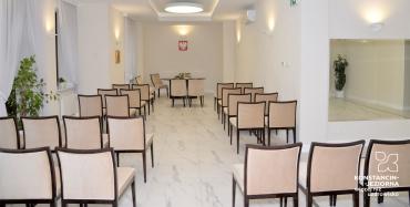 Wnętrze sali ślubów w willi Kamilin. Kremowe ściany, rzędy jasnych krzeseł. 
