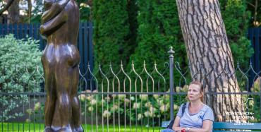 Rzeźba w ogrodzie, na która patrzy kobieta.