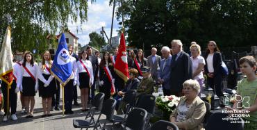 Starsi i młodzi ludzie ze sztandarami.