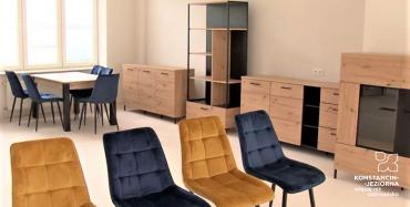 Wnętrze pomieszczenia z ustawionymi meblami - fotelami, krzesłami, stołe i szafkami, ściany w jasnym kolorze, po lewej stronie dużę okno