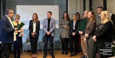 Grupa osób stoi w sali urzędu podczas świątecznego spotkania, w trakcie którego wręczane są podziękowania członkom Rady Seniorów.