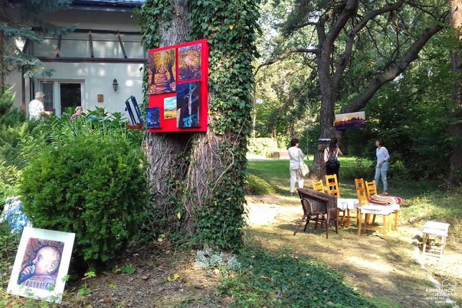 The garden in front of the cottage with a lot of trees among which there are paintings 