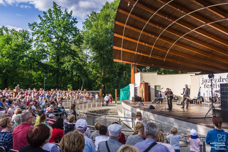 Amphitheater with a large audience, a group of musicians on the stage on the right 