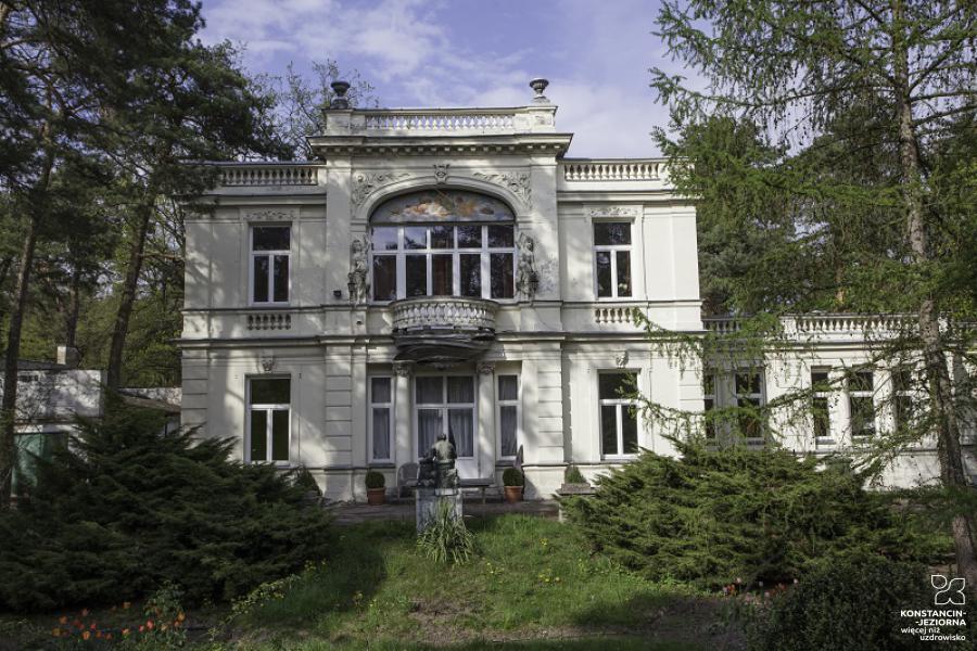 The richly decorated facade of the two-story building, with a colonnade on the pietrez and on the roof, a large semicircular topped balcony window 