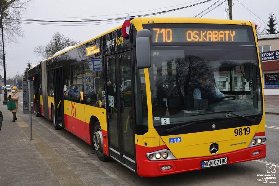 Pomarańczowo-czerwony autobus stoi na przystanku, nad przednią szybą wyświetlacz z numerem linii 710 i nazwą przystanka końcowego – os. Kabaty.