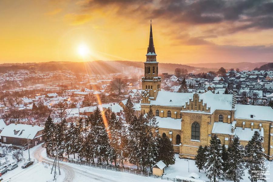 Aerial view of the neo-Gothic brick church illuminated by the morning sun in a winter landscape 