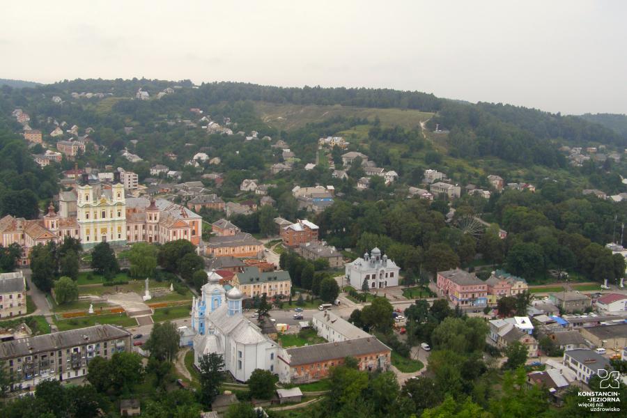 Vast panorama of the city seen from above, historic buildings visible, including a large monastery building on the left 