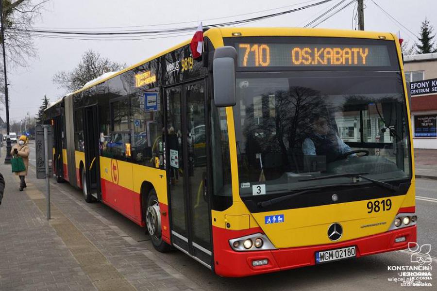 Pomarańczowo-czerwony autobus stoi na przystanku, nad przednią szybą wyświetlacz z numerem linii 710 i nazwą przystanka końcowego – os. Kabaty.