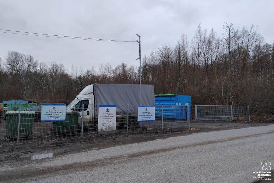 Na zdjęciu droga i brama wjazdowa na teren PSZOK, w tle furgonetka i kontenery na śmieci.