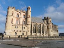 Duży kamienny zamek o renesansowej architekturze bryły z elementami gotyku, przed zamkiem ulica