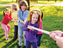 Pięcioro dzieci w wieku szkolnym bierze udział w zabawie ciągnięcia liny. 