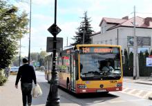 Ulica, po której jedzie czerwono-pomarańczowy autobus komunikacji miejskiej. Nad jego przednią szybą wyświetla się napis: 724 Metro Kabaty.