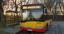 Pomarańczowo-czerwony autobus stoi na przystanku, nad przednią szybą wyświetlany jest numer linii 264 i informacja: odjazd za 7 minut..