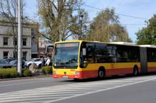 Ulica, po której jedzie czerwono-pomarańczowy autobus komunikacji miejskiej. Nad jego przednią szybą wyświetla się napis: 710.