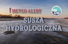 Na górze czerwony napis meteo alert poprzedzony wykrzyknikiem. Obok niego logo Instytutu Meteorologii i Gospodarki Wodnej – niebieski okrąg z białymi literami IMGW, poniżej niebieski napis: susza hydrologiczna  W tle rzeka. 