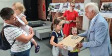 Starszy mężczyzna wręcza dzieciom komputer przenośny w pudełku.